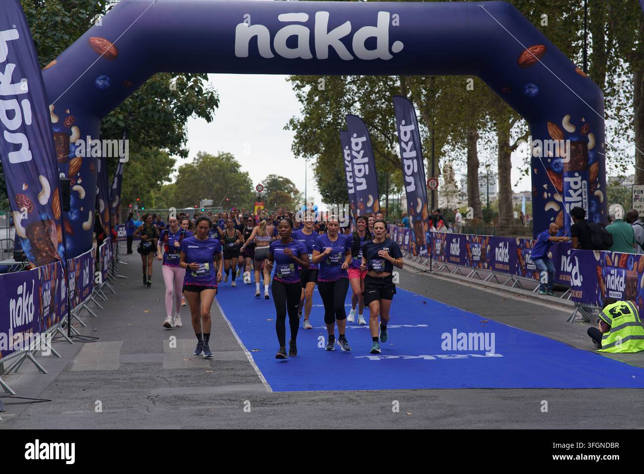 Coureuses en tenues festives assorties célébrant à l'arrivée de l'événement de course féminine La Parisienne sur une rue de Paris en France. Banque D'Images