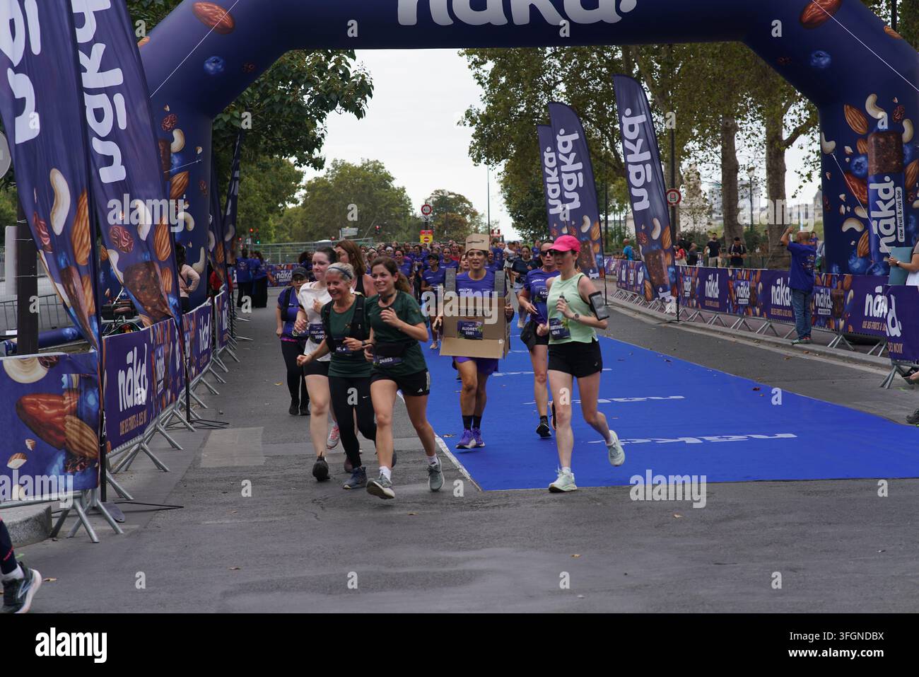 Coureuses en tenues festives assorties célébrant à l'arrivée de l'événement de course féminine La Parisienne sur une rue de Paris en France. Banque D'Images