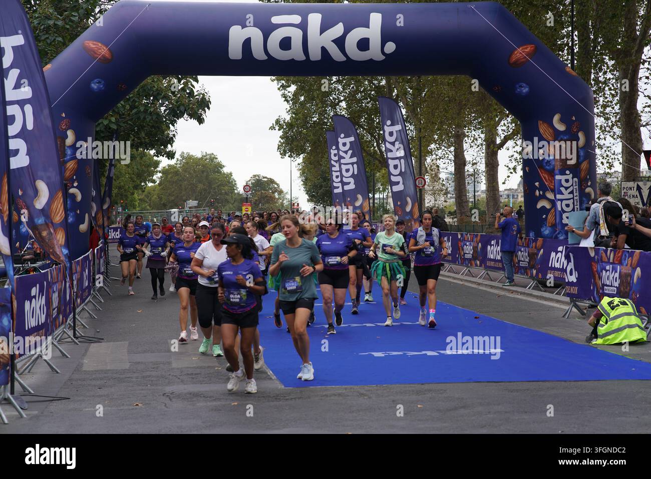 Coureuses en tenues festives assorties célébrant à l'arrivée de l'événement de course féminine La Parisienne sur une rue de Paris en France. Banque D'Images