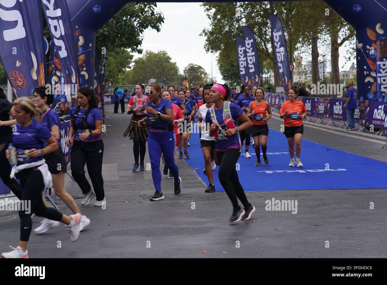 Coureuses en tenues festives assorties célébrant à l'arrivée de l'événement de course féminine La Parisienne sur une rue de Paris en France. Banque D'Images