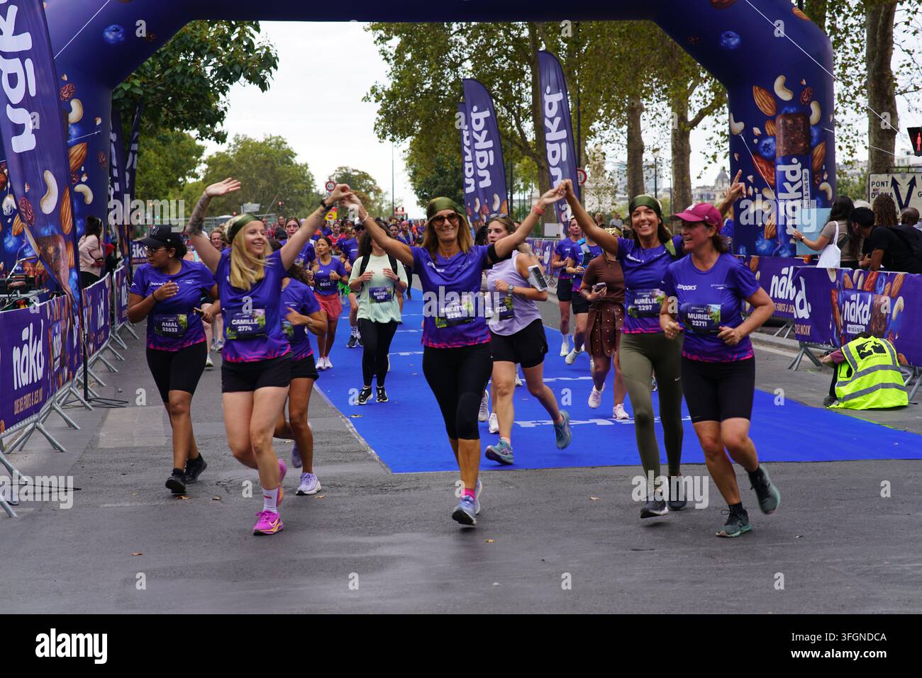 Coureuses en tenues festives assorties célébrant à l'arrivée de l'événement de course féminine La Parisienne sur une rue de Paris en France. Banque D'Images