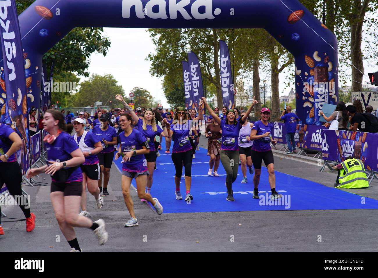 Coureuses en tenues festives assorties célébrant à l'arrivée de l'événement de course féminine La Parisienne sur une rue de Paris en France. Banque D'Images