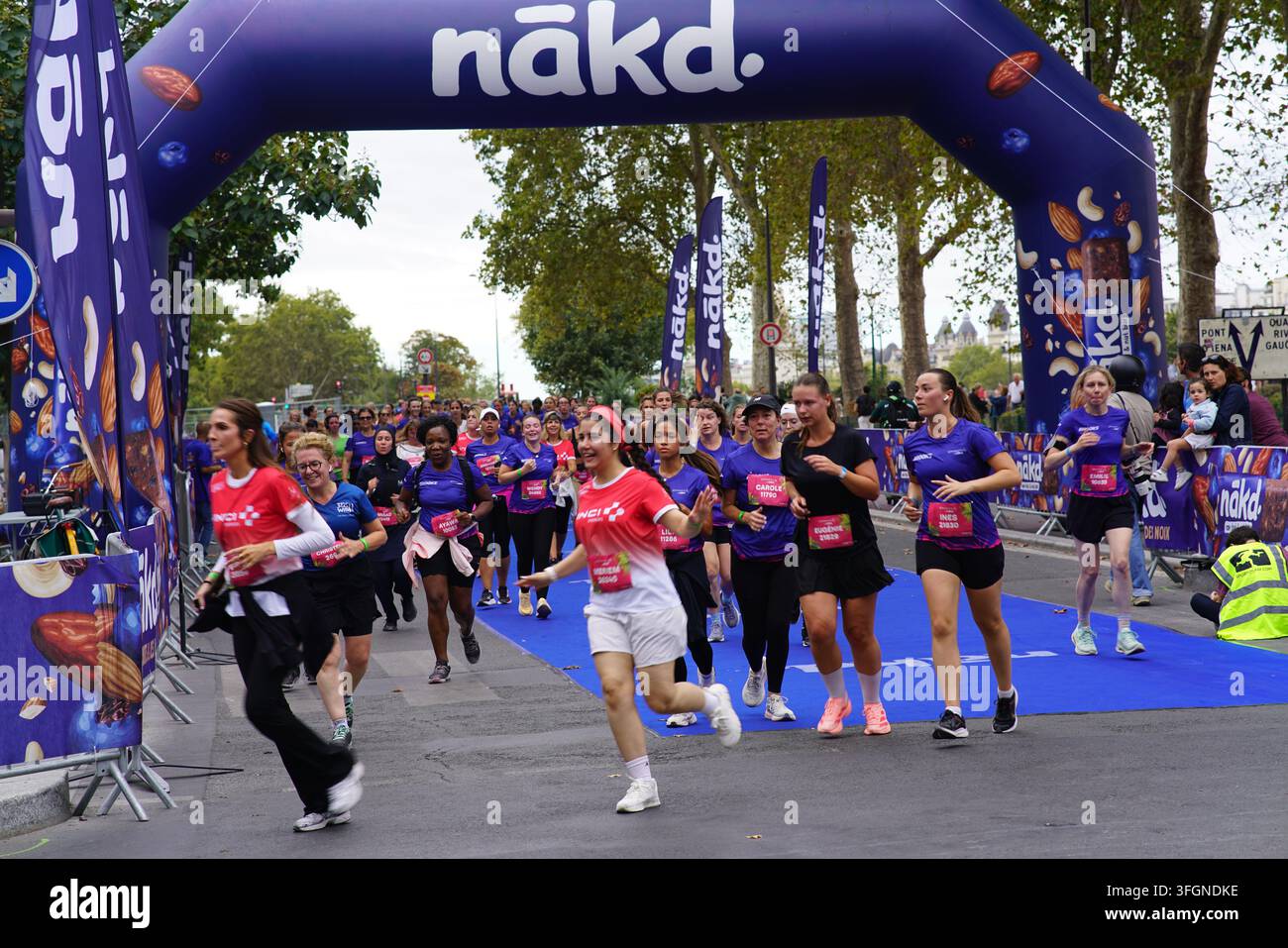 Coureuses en tenues festives assorties célébrant à l'arrivée de l'événement de course féminine La Parisienne sur une rue de Paris en France. Banque D'Images