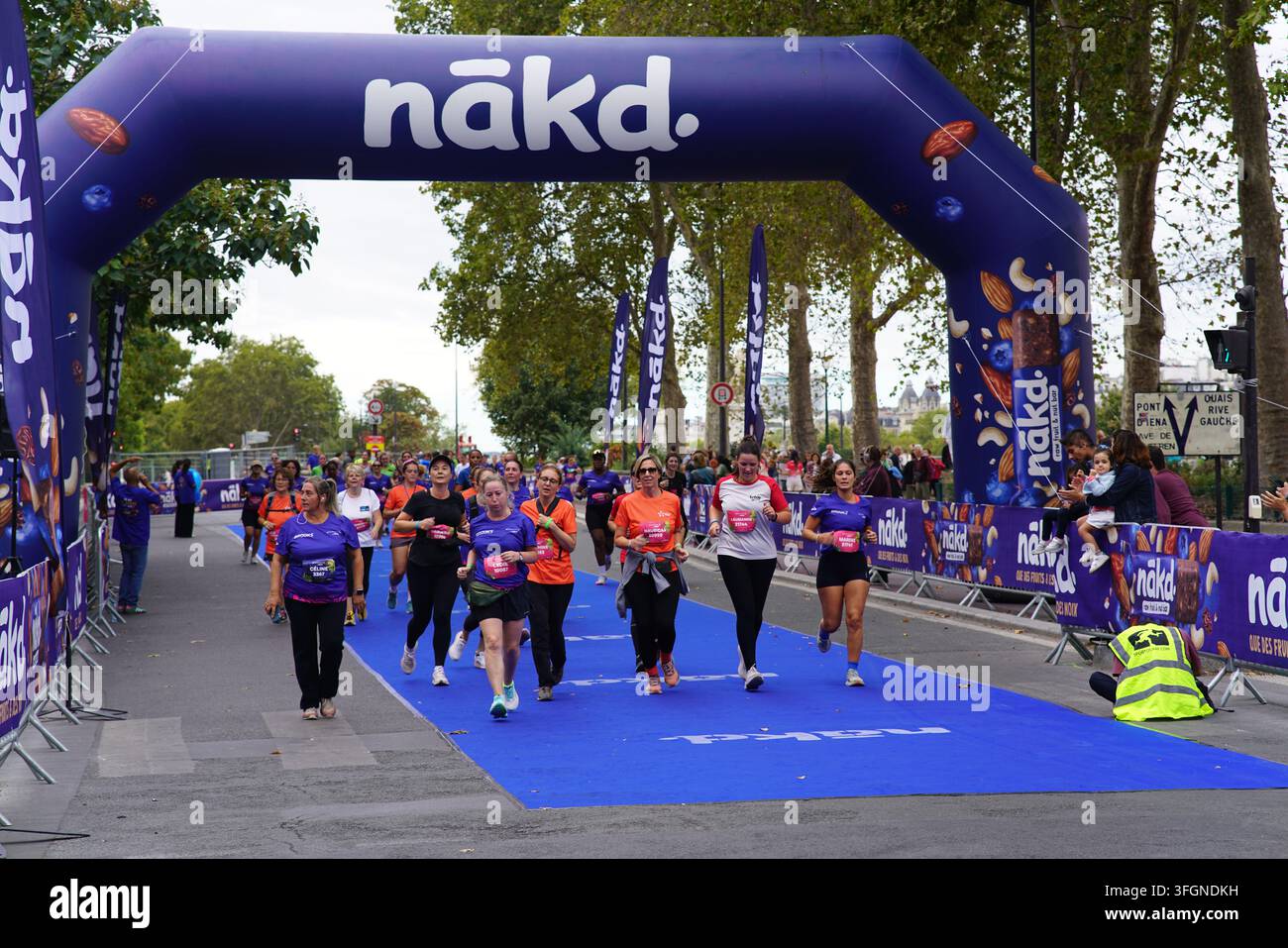 Coureuses en tenues festives assorties célébrant à l'arrivée de l'événement de course féminine La Parisienne sur une rue de Paris en France. Banque D'Images
