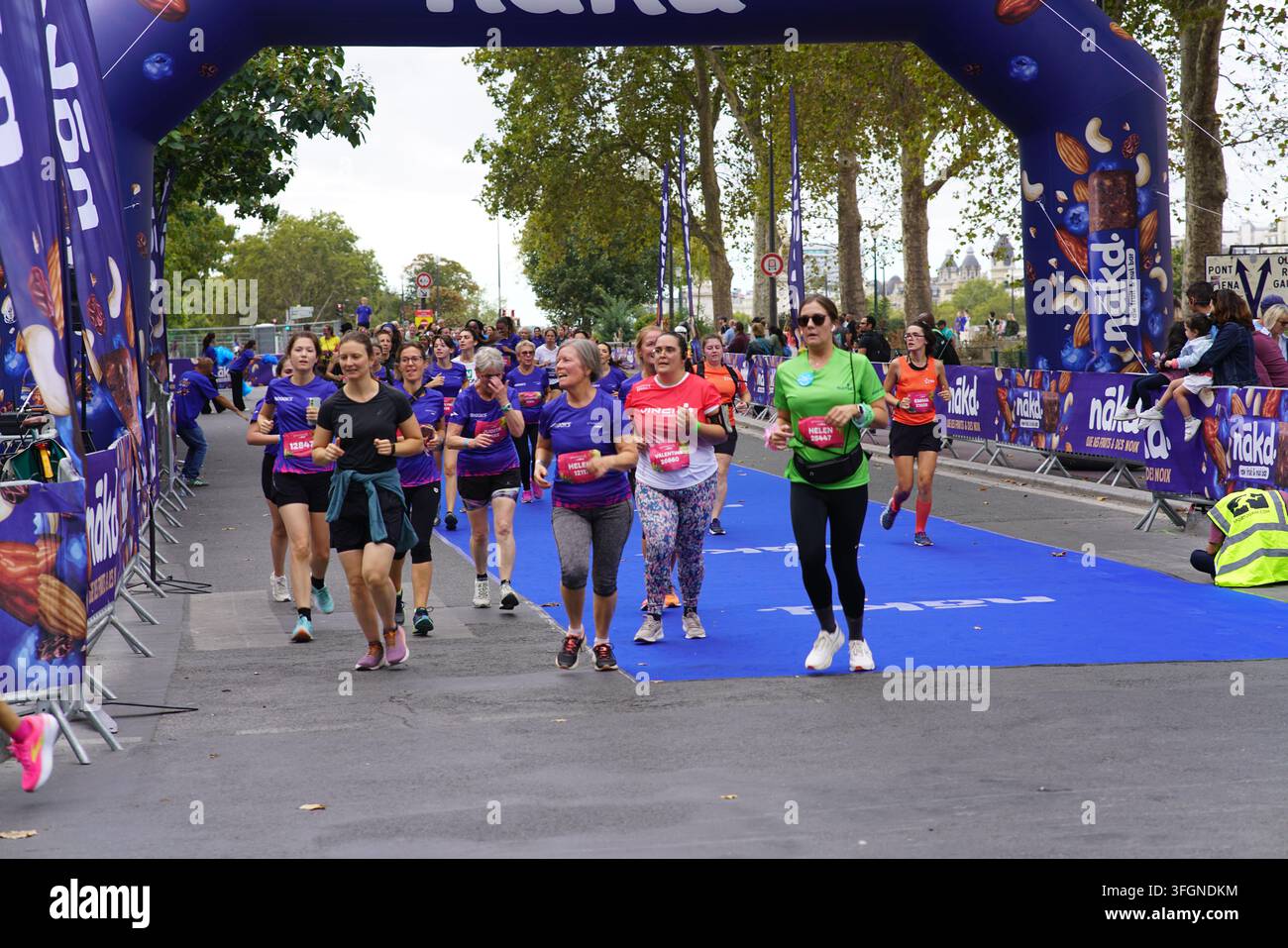 Coureuses en tenues festives assorties célébrant à l'arrivée de l'événement de course féminine La Parisienne sur une rue de Paris en France. Banque D'Images