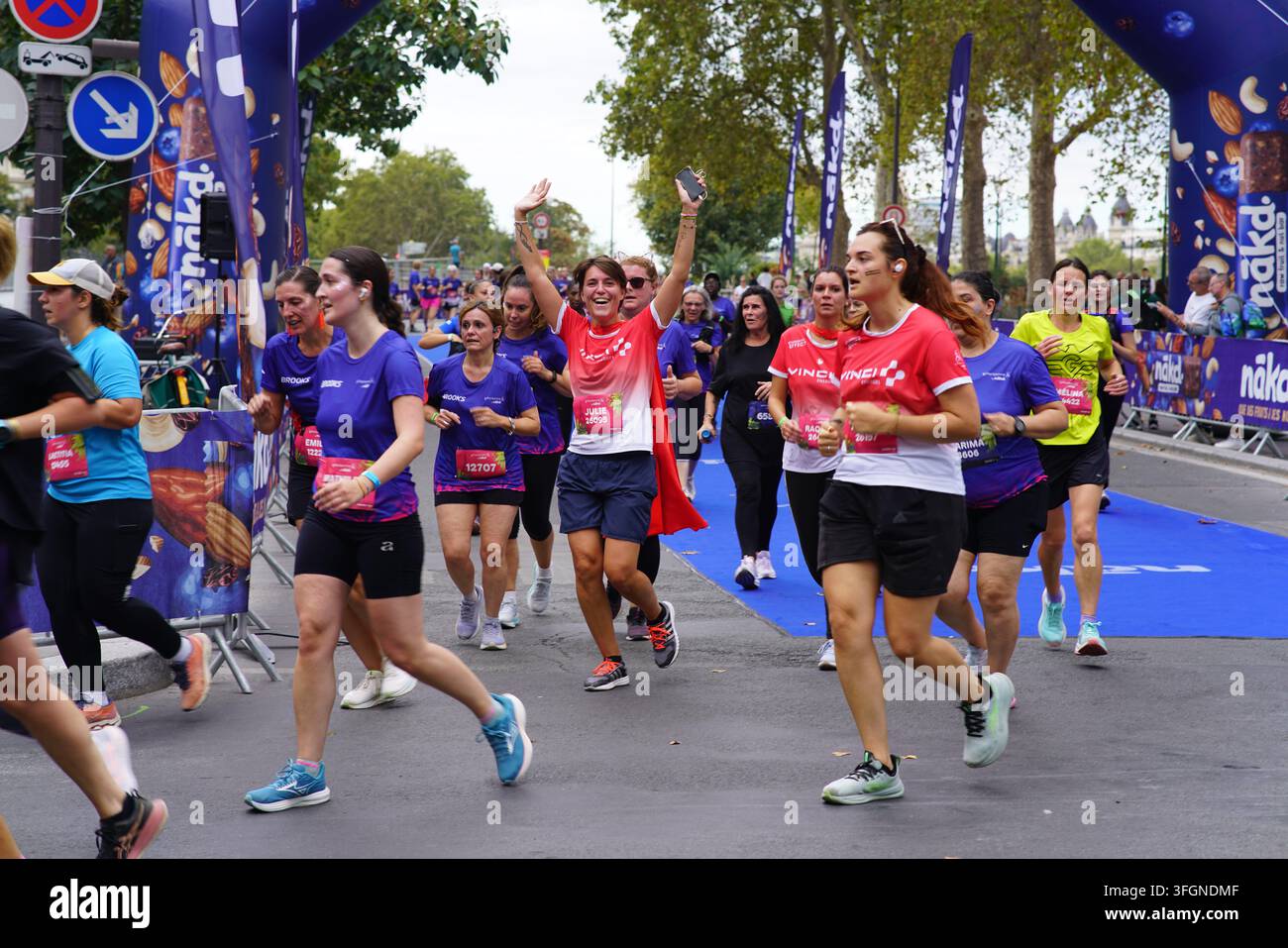 Coureuses en tenues festives assorties célébrant à l'arrivée de l'événement de course féminine La Parisienne sur une rue de Paris en France. Banque D'Images