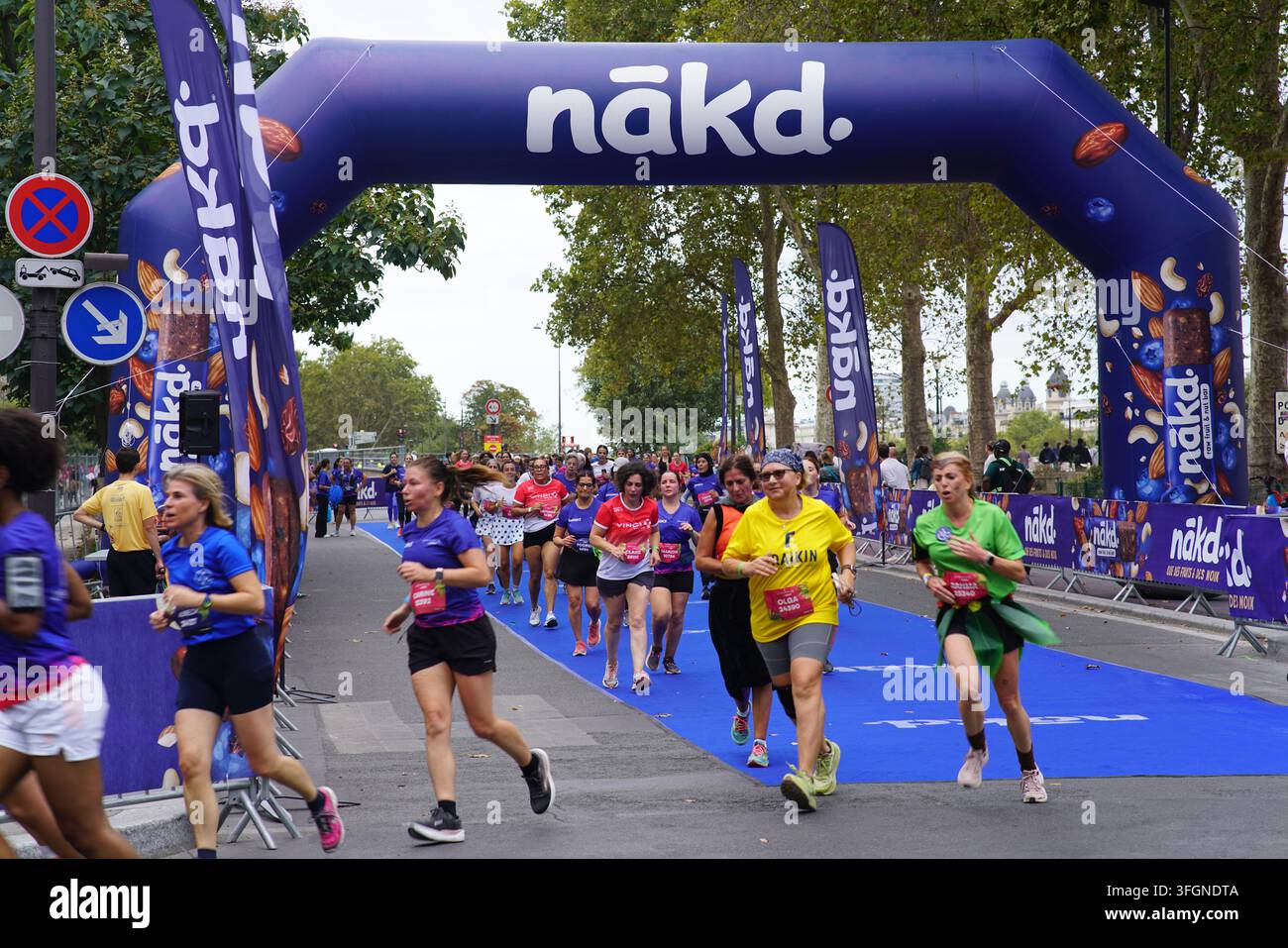 Coureuses en tenues festives assorties célébrant à l'arrivée de l'événement de course féminine La Parisienne sur une rue de Paris en France. Banque D'Images