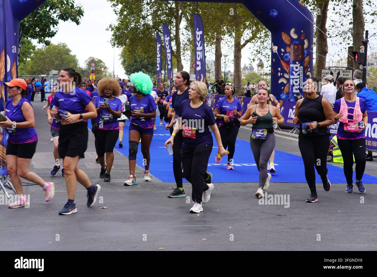 Coureuses en tenues festives assorties célébrant à l'arrivée de l'événement de course féminine La Parisienne sur une rue de Paris en France. Banque D'Images