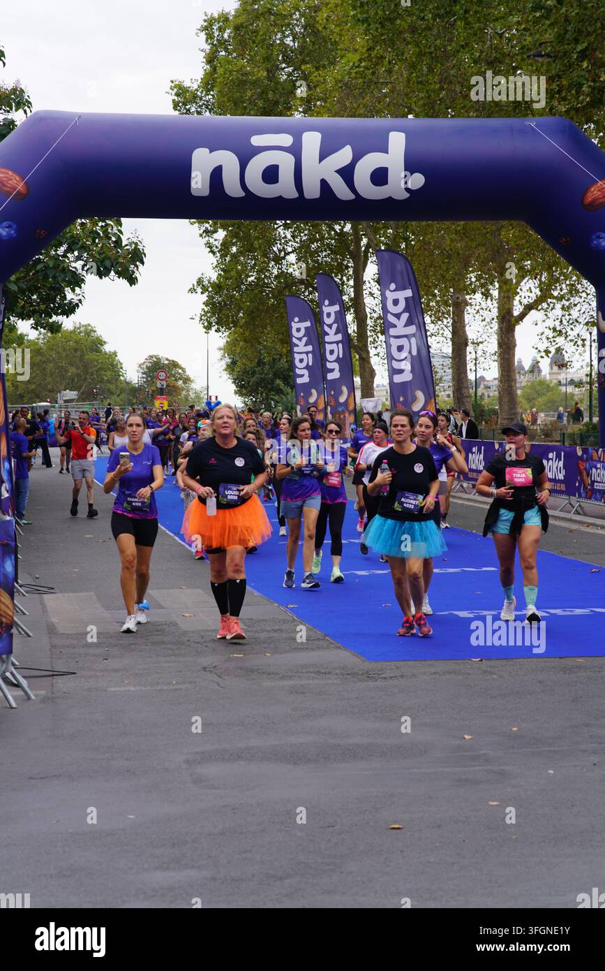 Coureuses en tenues festives assorties célébrant à l'arrivée de l'événement de course féminine La Parisienne sur une rue de Paris en France. Banque D'Images
