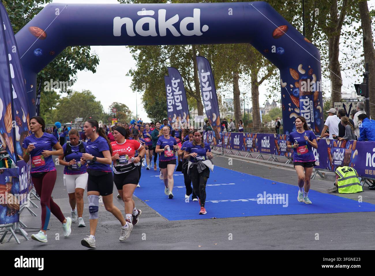 Coureuses en tenues festives assorties célébrant à l'arrivée de l'événement de course féminine La Parisienne sur une rue de Paris en France. Banque D'Images