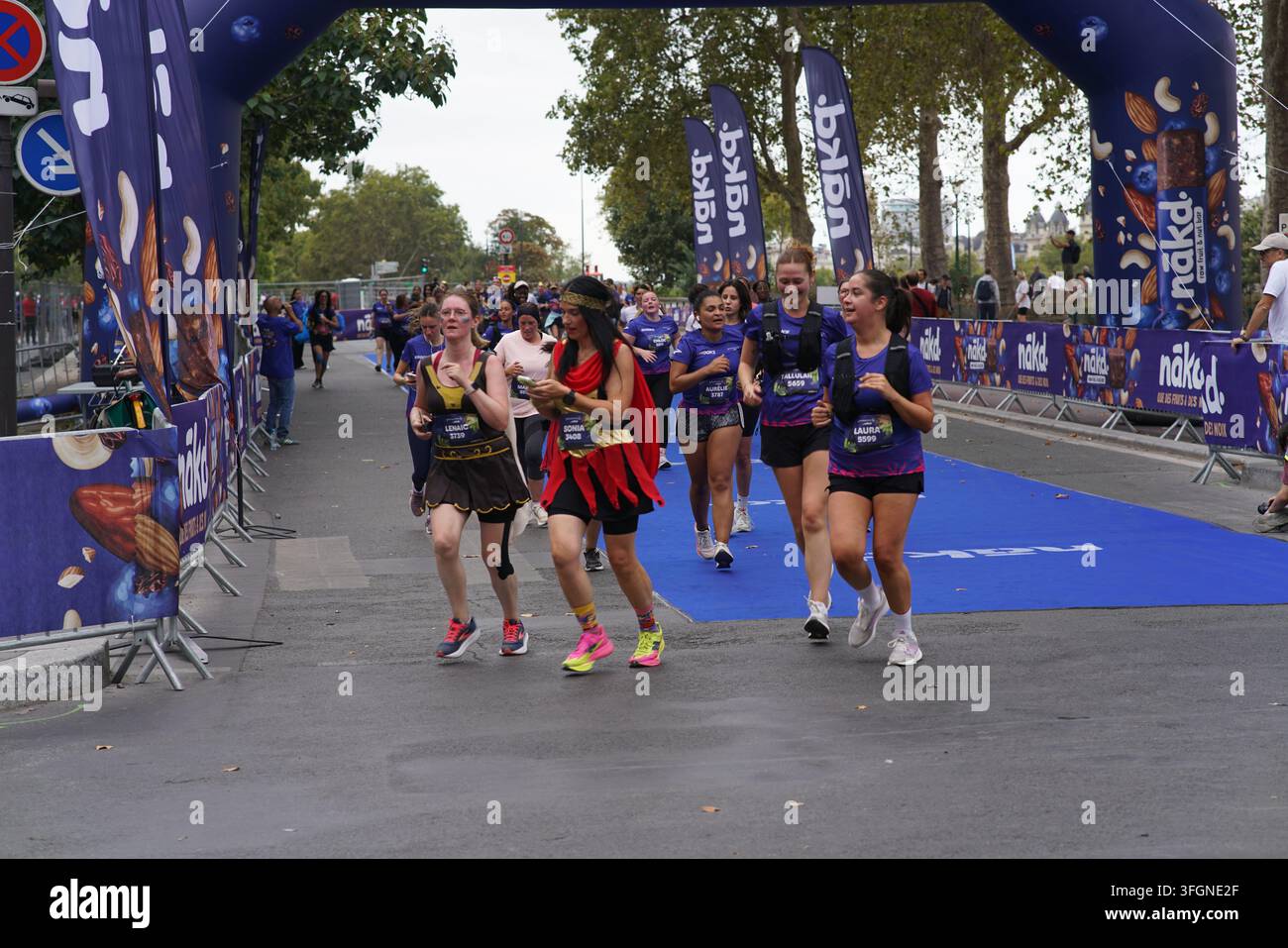 Coureuses en tenues festives assorties célébrant à l'arrivée de l'événement de course féminine La Parisienne sur une rue de Paris en France. Banque D'Images