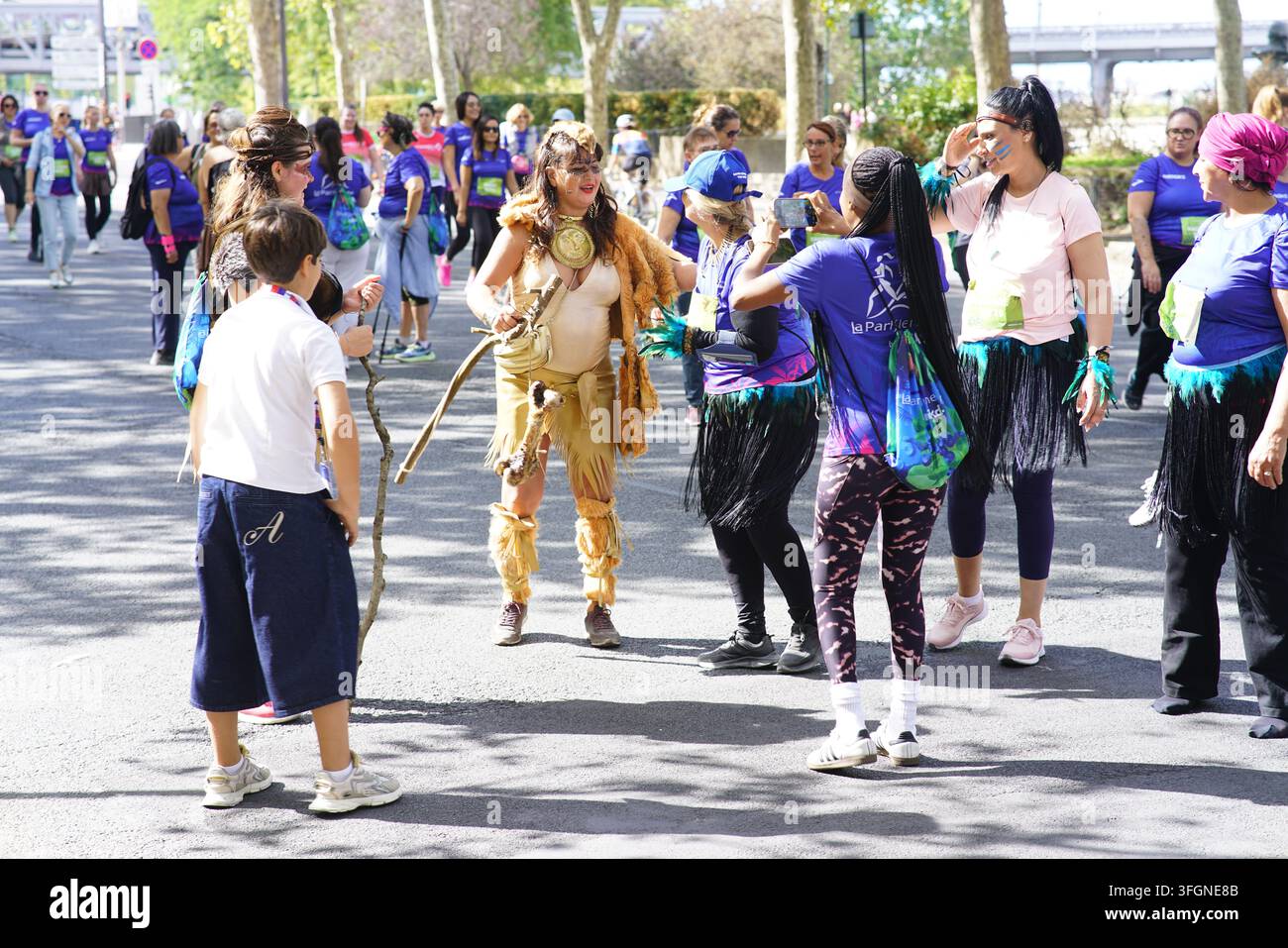 Coureurs en costume et un enfant en train de parler sur le parcours lors de l'événement de course féminine La Parisienne sur une rue ensoleillée à Paris, France. Banque D'Images