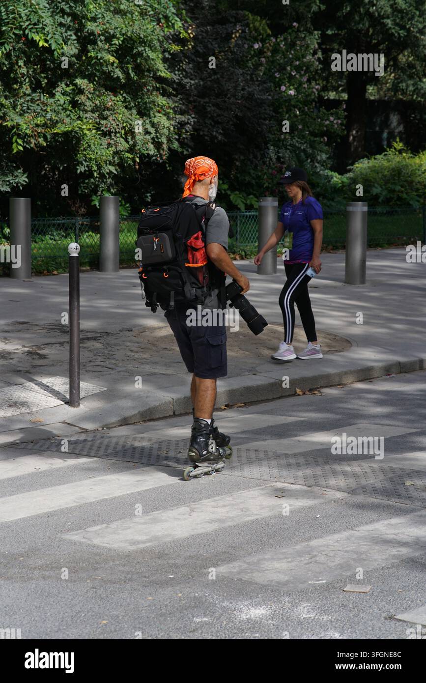 Homme en patins à roulettes portant du matériel photographique à côté des participantes lors de l'événement de course féminine La Parisienne à Paris, France. Banque D'Images