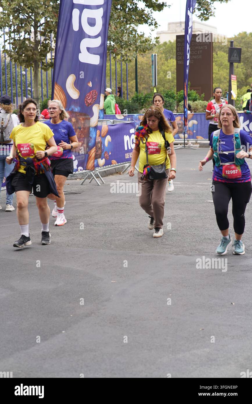 Coureuses en tenues festives assorties célébrant à l'arrivée de l'événement de course féminine La Parisienne sur une rue de Paris en France. Banque D'Images