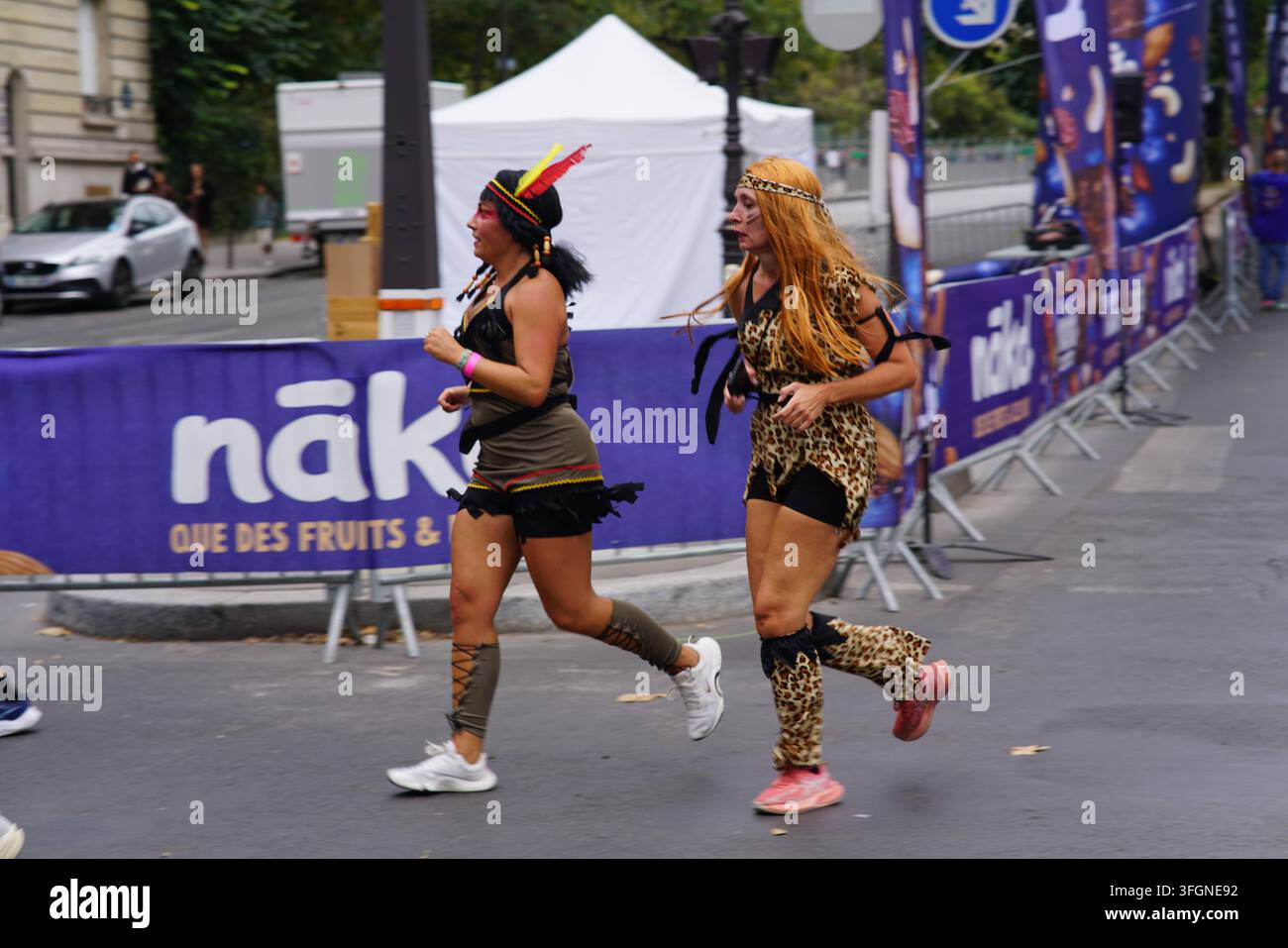 Coureuses en tenues festives assorties célébrant à l'arrivée de l'événement de course féminine La Parisienne sur une rue de Paris en France. Banque D'Images