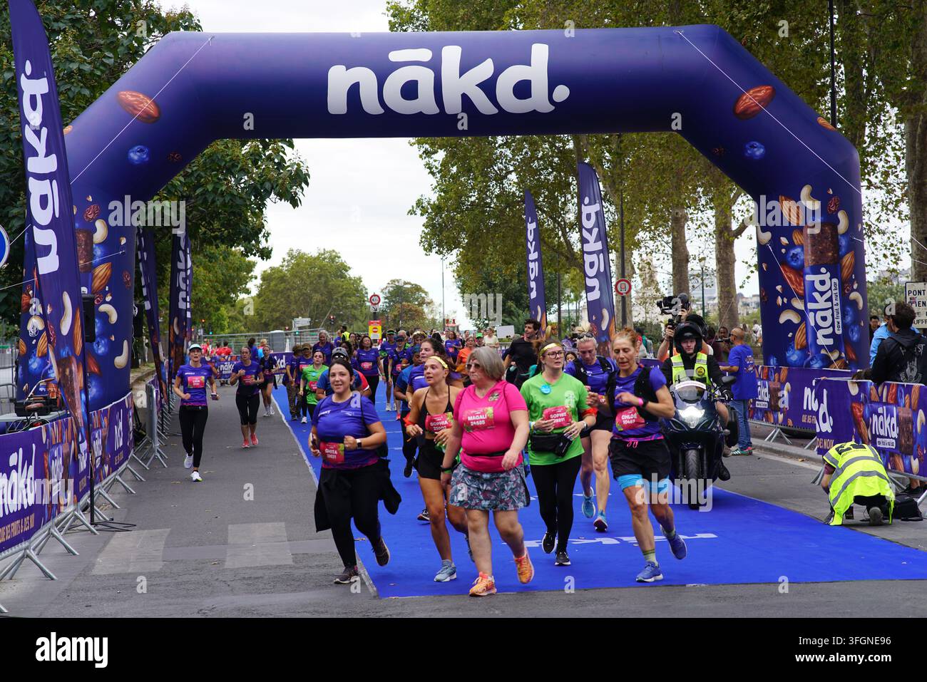 Coureuses en tenues festives assorties célébrant à l'arrivée de l'événement de course féminine La Parisienne sur une rue de Paris en France. Banque D'Images