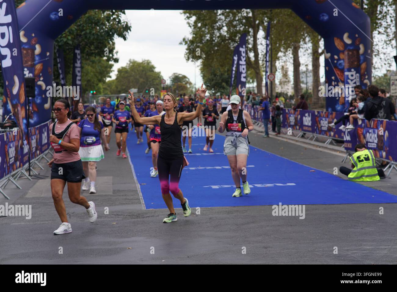 Coureuses en tenues festives assorties célébrant à l'arrivée de l'événement de course féminine La Parisienne sur une rue de Paris en France. Banque D'Images