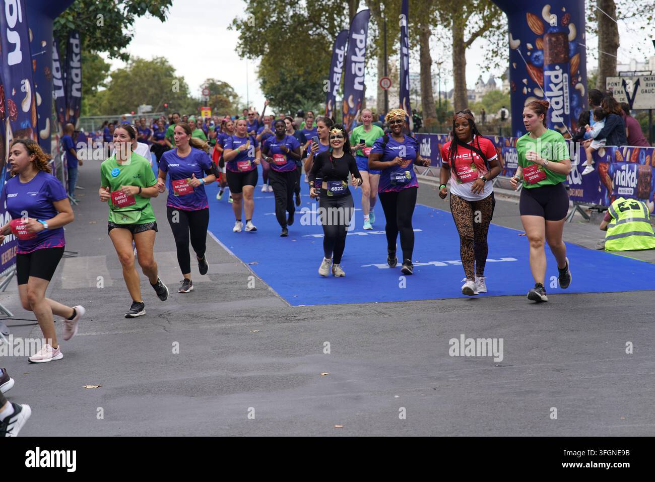 Coureuses en tenues festives assorties célébrant à l'arrivée de l'événement de course féminine La Parisienne sur une rue de Paris en France. Banque D'Images