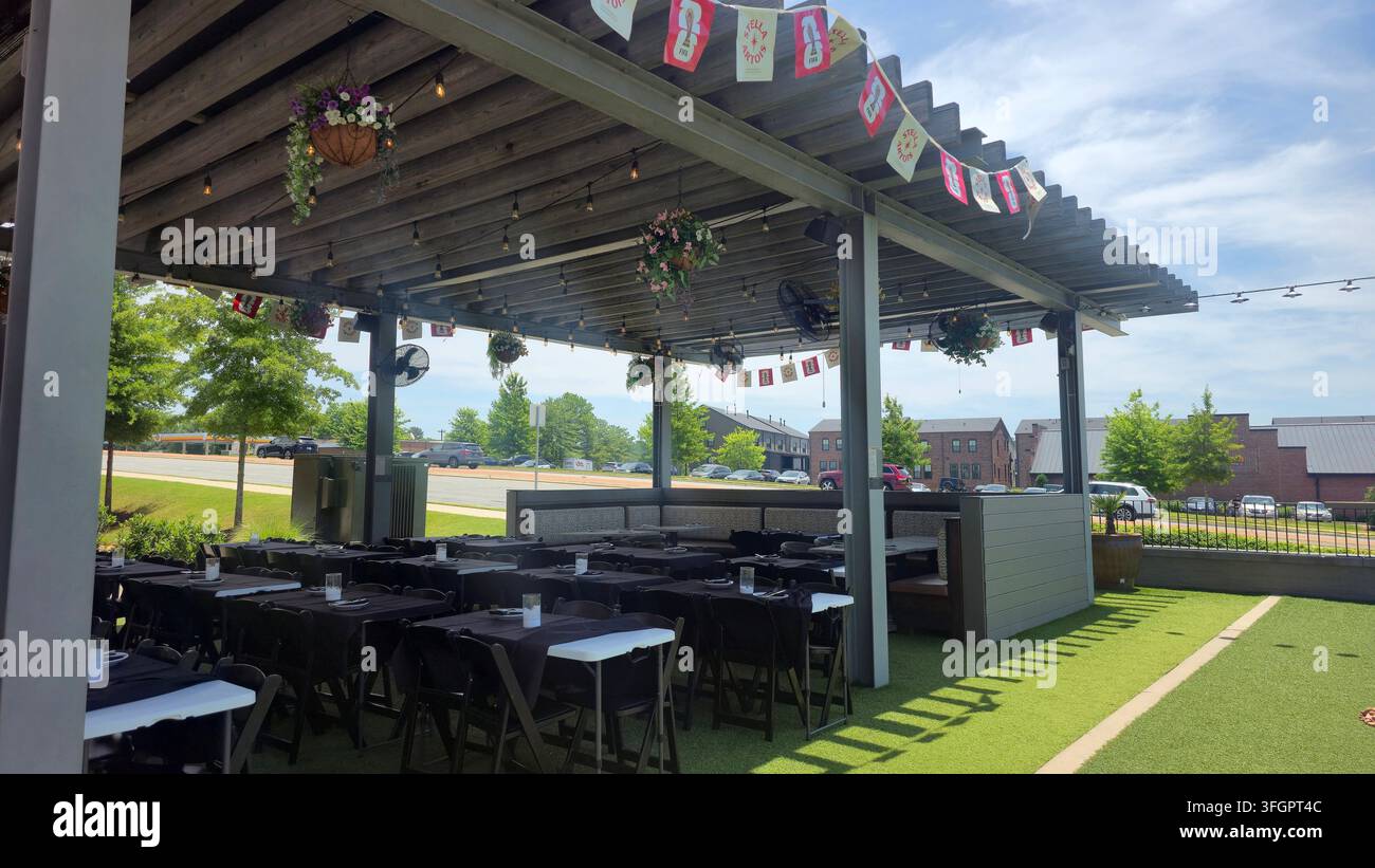 Terrasse de restaurant en plein air avec des tables dressées pour le dîner sous une pergola couverte Banque D'Images
