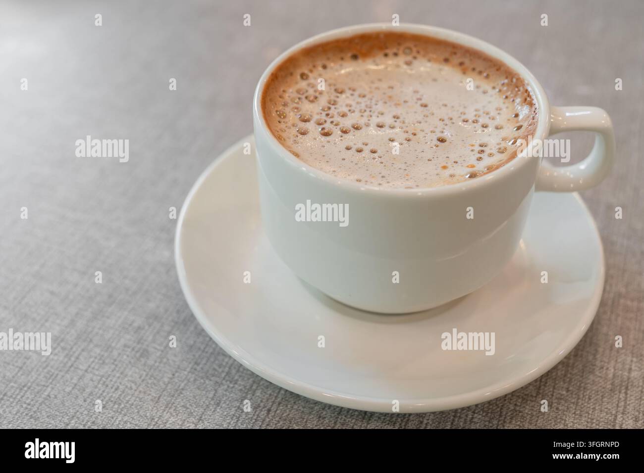 Une tasse de café crémeux fraîchement préparée, surmontée d'une mousse fine, servie dans une tasse et soucoupe en céramique blanche Banque D'Images