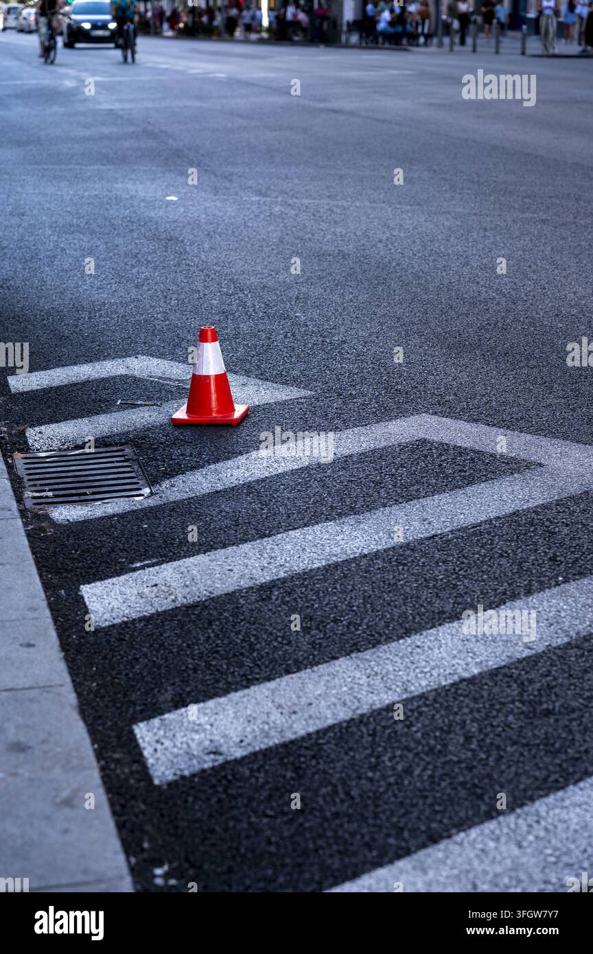 Cône de signalisation orange posé sur une route asphaltée avec marquage routier Banque D'Images