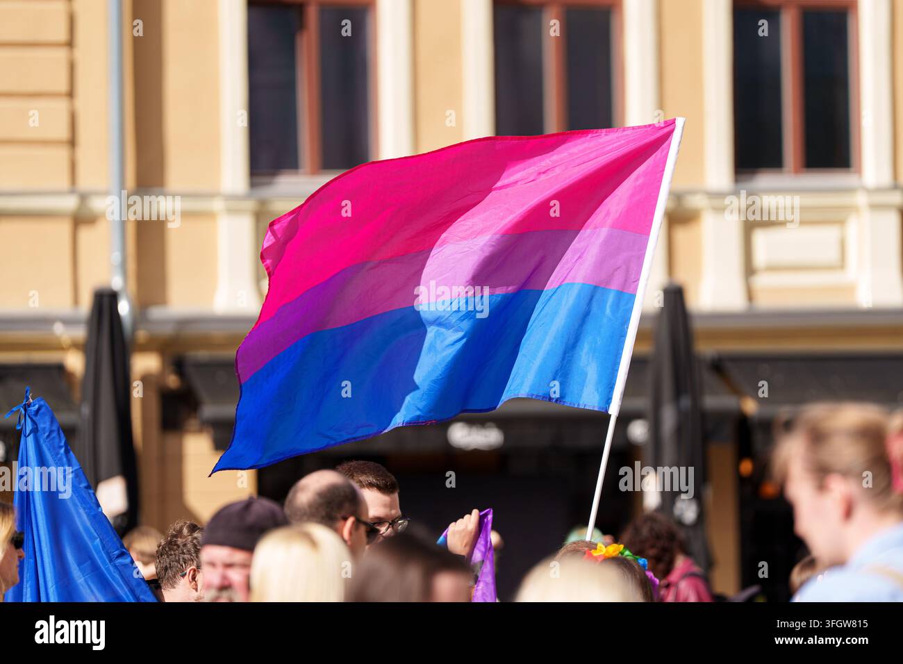 Drapeau de fierté bisexuel flottant au-dessus d'une foule en plein air devant un bâtiment historique, événement de fierté LGBTQ et concept de droits égaux. Photo de haute qualité Banque D'Images
