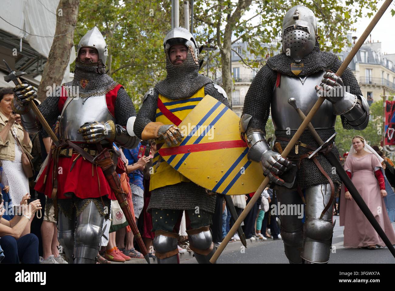 Des reconstitutionnistes historiques vêtus d'une armure de plaques médiévale complète, d'une cotte de mailles et portant des armes ainsi qu'un bouclier héraldique défilent lors d'une parade de rue à Paris Banque D'Images