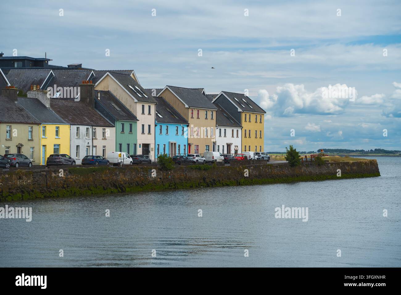 Le rythme de la façade riveraine émerge grâce aux maisons colorées, aux toits en ardoise et aux voitures garées le long du quai en pierre de The Long Walk à Galway pour l'architecture irlandaise Banque D'Images
