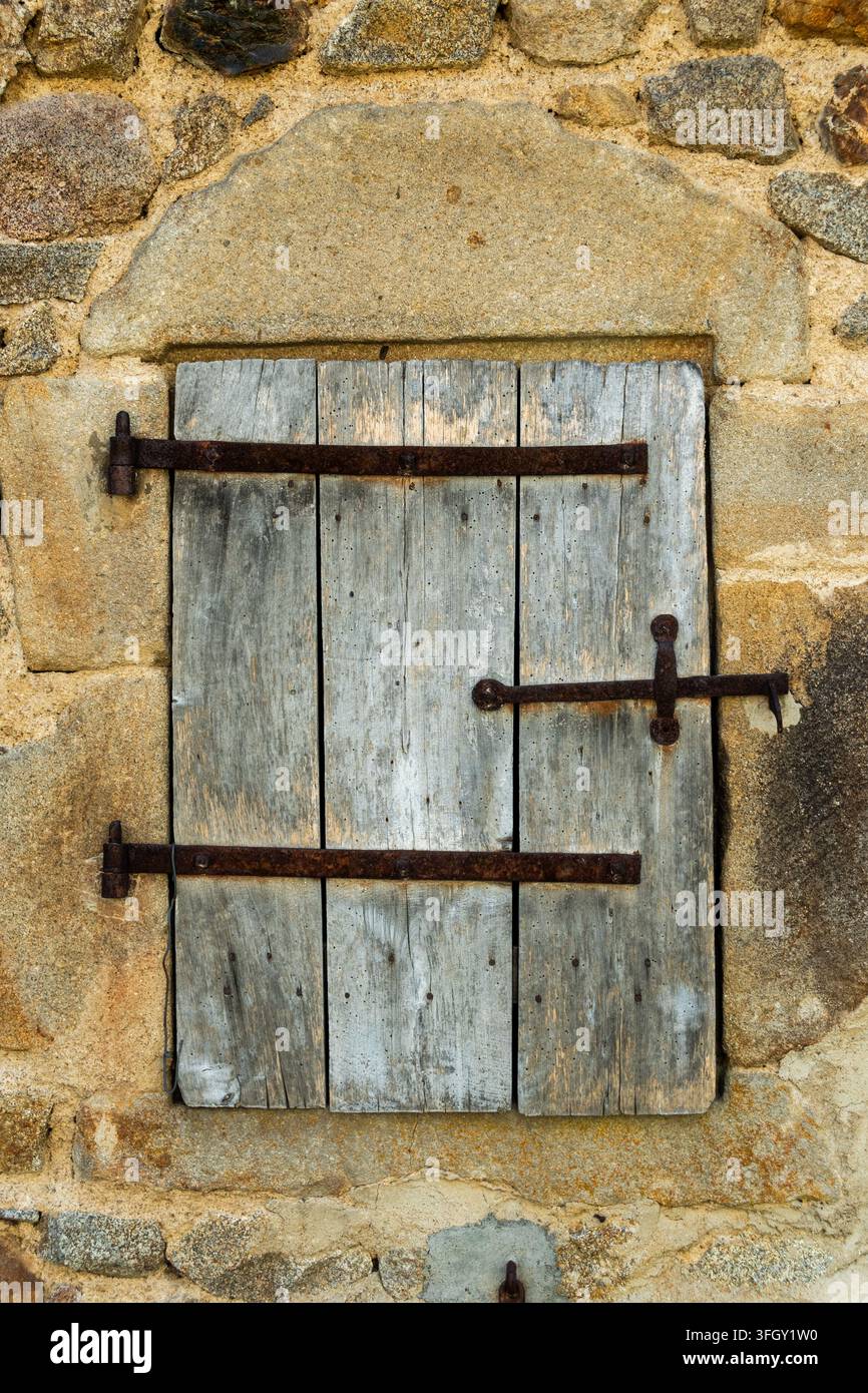 Ancienne fenêtre en bois fermée dans un mur de maison en pierre, Auvergne, France Banque D'Images