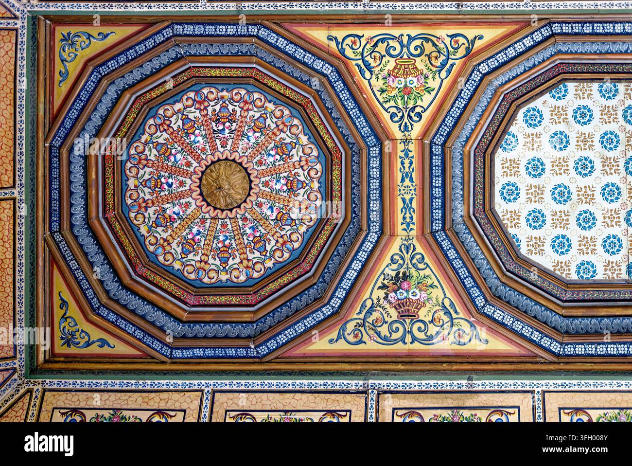 Détails en cadrage complet d'un panneau de plafond en bois peint à la main traditionnel présentant des médaillons octogonaux complexes, des motifs floraux et des bordures arabesques à Banque D'Images