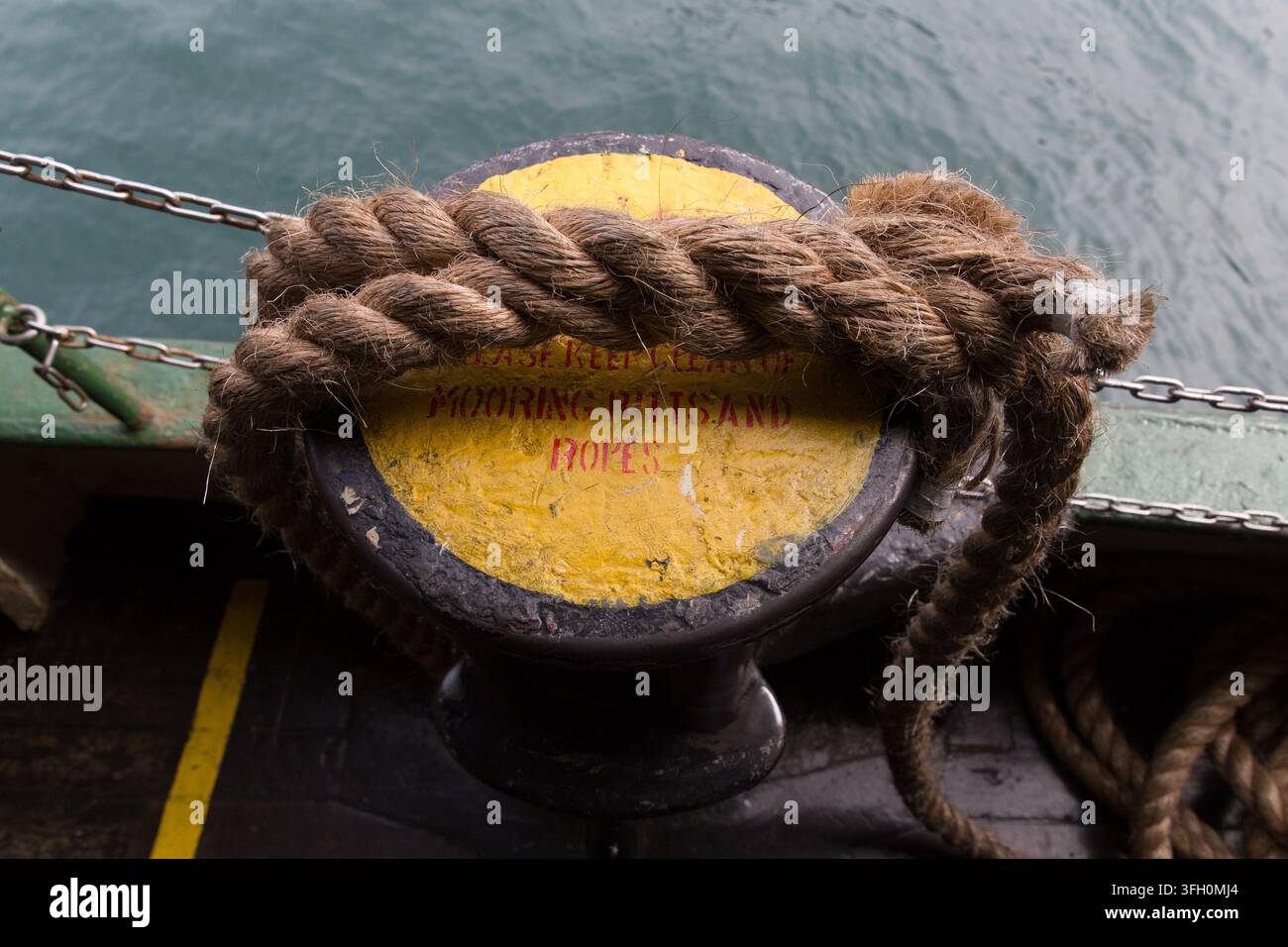 L'équipage enroule une épaisse corde autour d'un bitte d'amarrage pour arrimer un Star Ferry dans le Victoria Harbour de Hong Kong. Banque D'Images