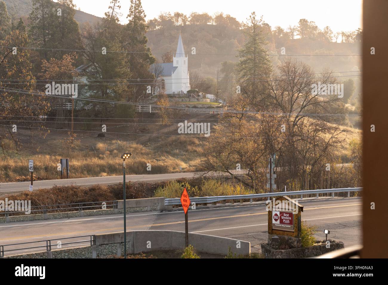 À Mariposa, CA, une vue autoroutière montre l'église catholique Saint-Joseph sur une colline derrière la BW Yosemite Way Station près de travaux routiers actifs. Banque D'Images