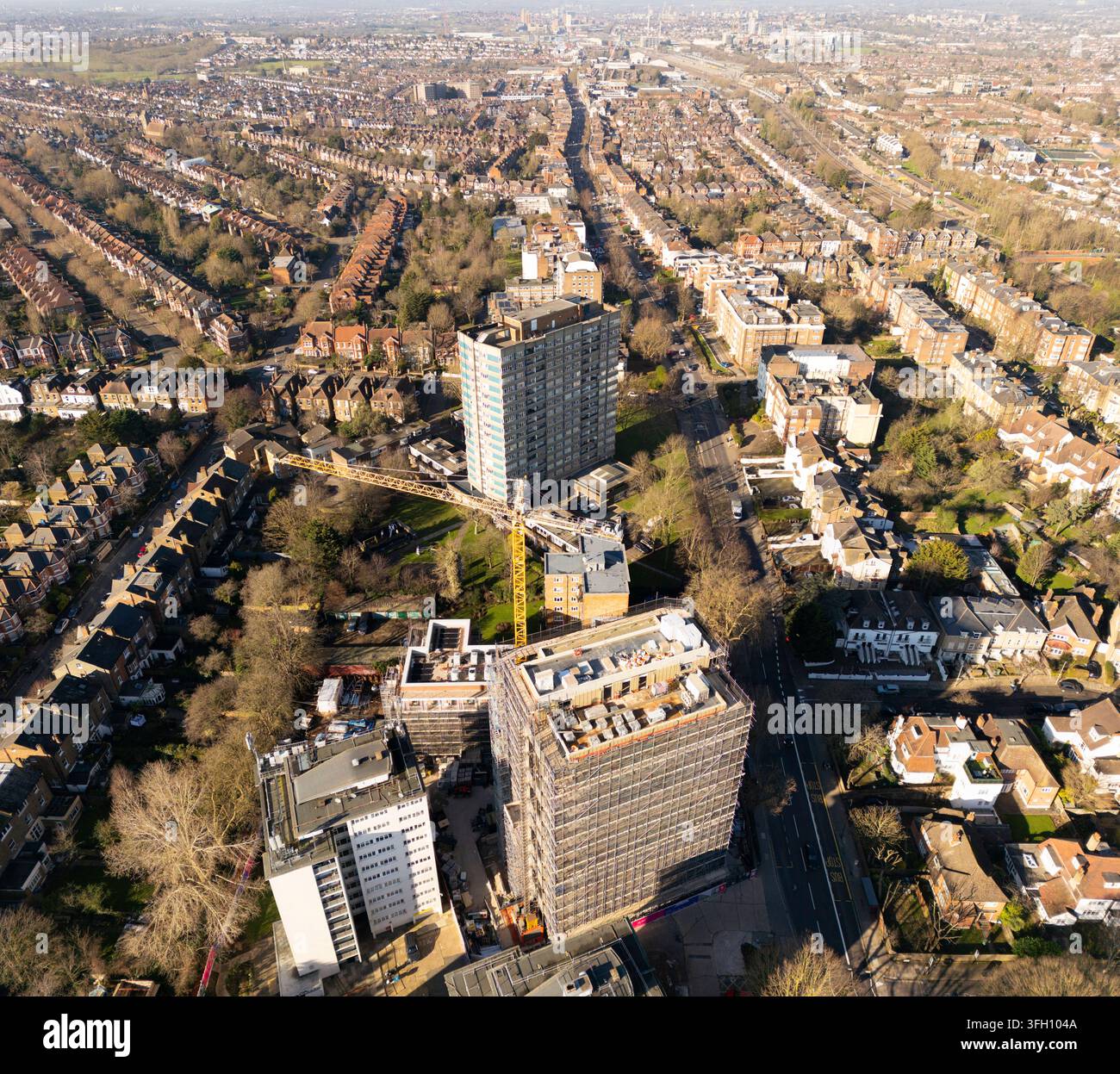 Des ouvriers manœuvrent une grue pour redévelopper Windmill Court sur Shoot Up Hill, Kilburn, Londres, en élargissant le logement résidentiel local. Banque D'Images