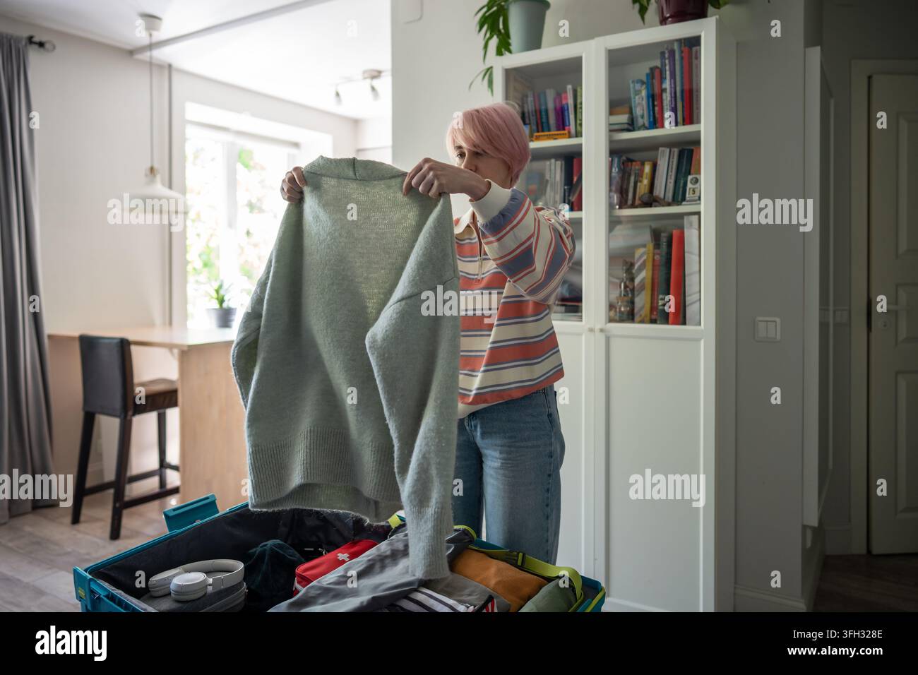 Femme vérifiant les vêtements pour le voyage de vacances avant d’emballer les affaires dans une valise à la maison dans la chambre. Banque D'Images