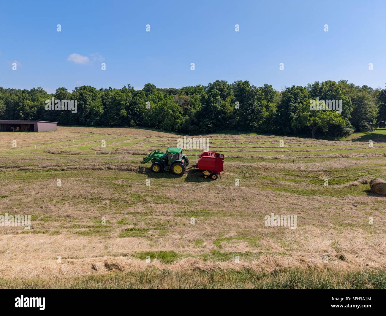 Tracteur faisant des balles de foin dans un champ rural de l'Ontario Banque D'Images