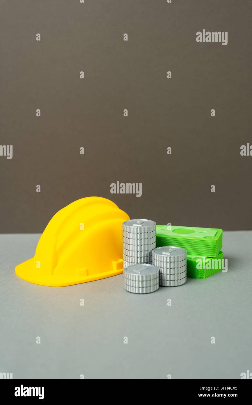 Un casque de sécurité jaune et de l'argent liquide avec des pièces. Concept des revenus de l'industrie de la construction et des salaires des ouvriers. Symbole de projets de construction rentables et pa Banque D'Images