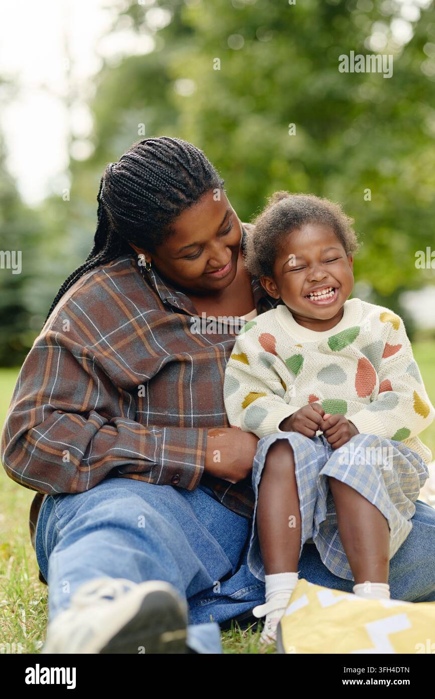 Mère noire heureuse se liant avec sa fille riante dans le parc Banque D'Images