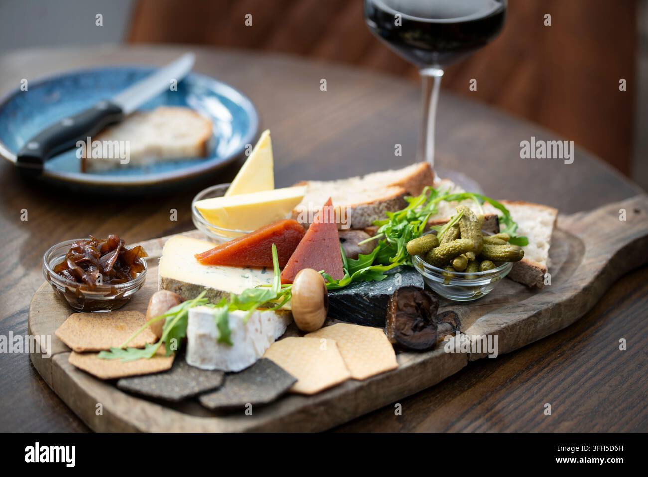 Un étalage coloré de fromages et de viandes disposés magnifiquement sur une planche en bois, parfait pour partager. Banque D'Images