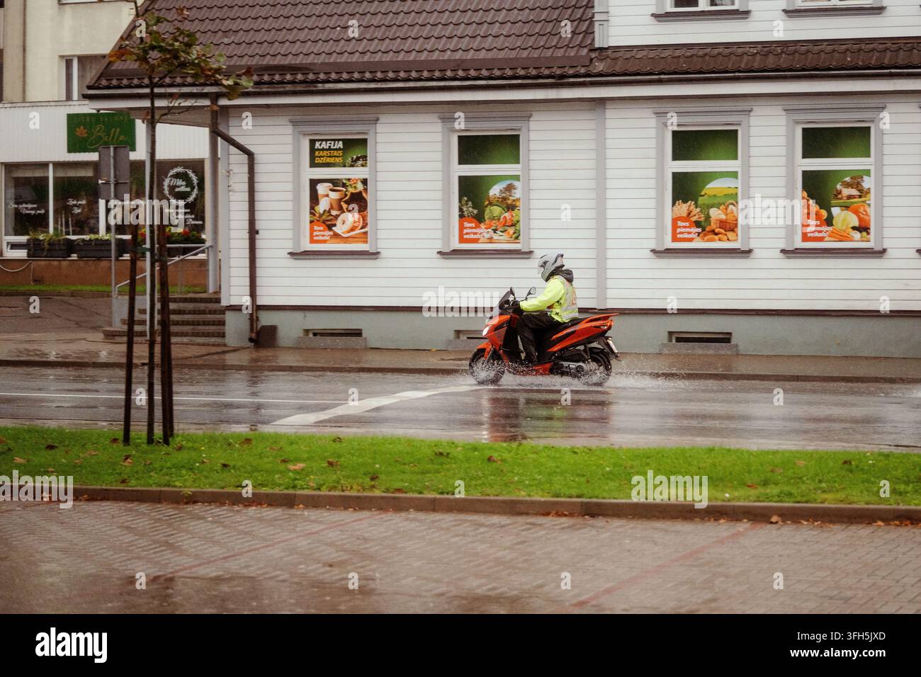 VALMIERA, LETTONIE - 1ER SEPTEMBRE 2026 : Apprenti motard roule sous une forte pluie pendant une leçon de formation sur une rue mouillée de la ville Banque D'Images