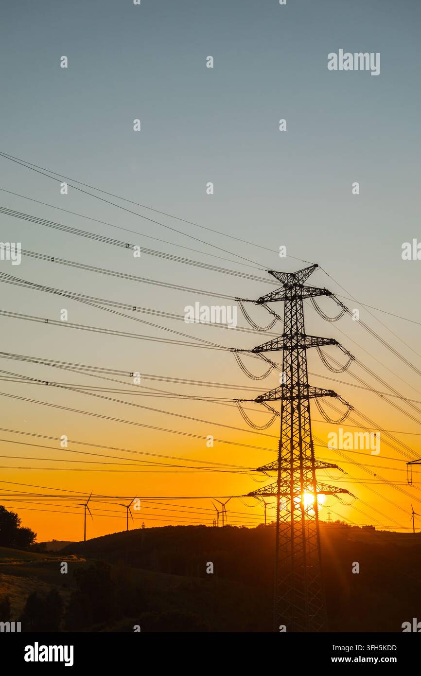 Tour de transmission d'énergie et éoliennes au coucher du soleil Banque D'Images