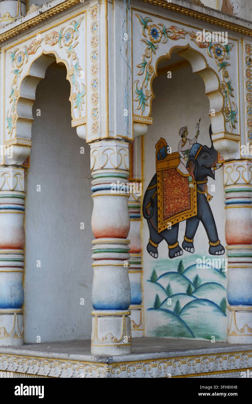 Peinture murale ornée d'un éléphant indien encadrée par une niche de temple en arc décoratif avec des colonnes colorées à Pushkar, Rajasthan, Inde. Banque D'Images