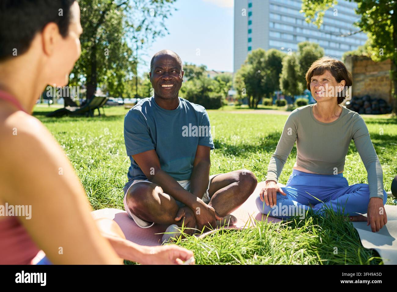 Diverses personnes d'âge moyen pratiquant le yoga en plein air dans un parc Banque D'Images