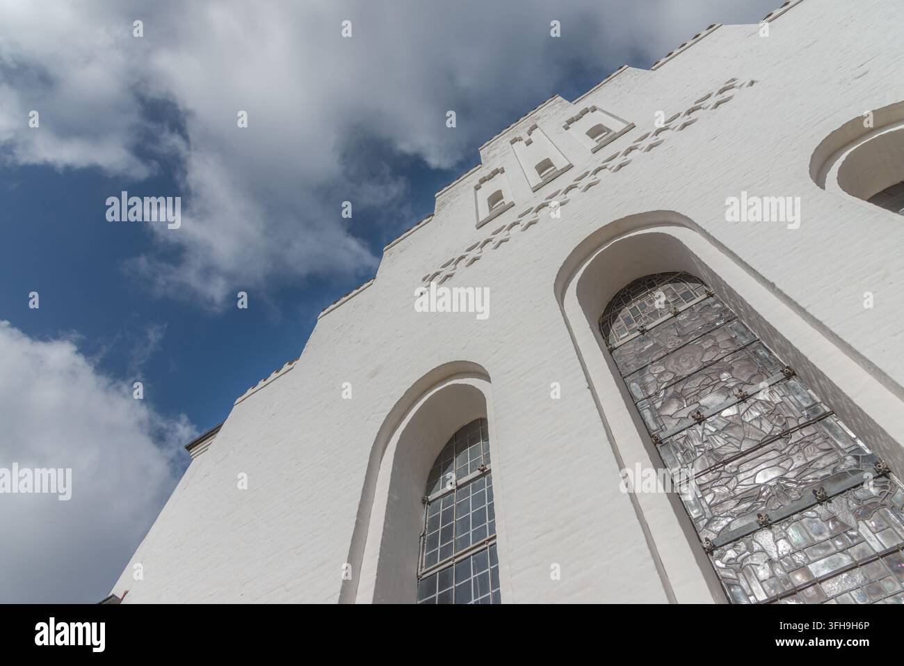Un plan dramatique en contre-plongée de l'église blanche de Juelsminde, mettant en valeur ses fenêtres cintrées, ses détails de maçonnerie complexes et un pignon à gradins à nouveau Banque D'Images