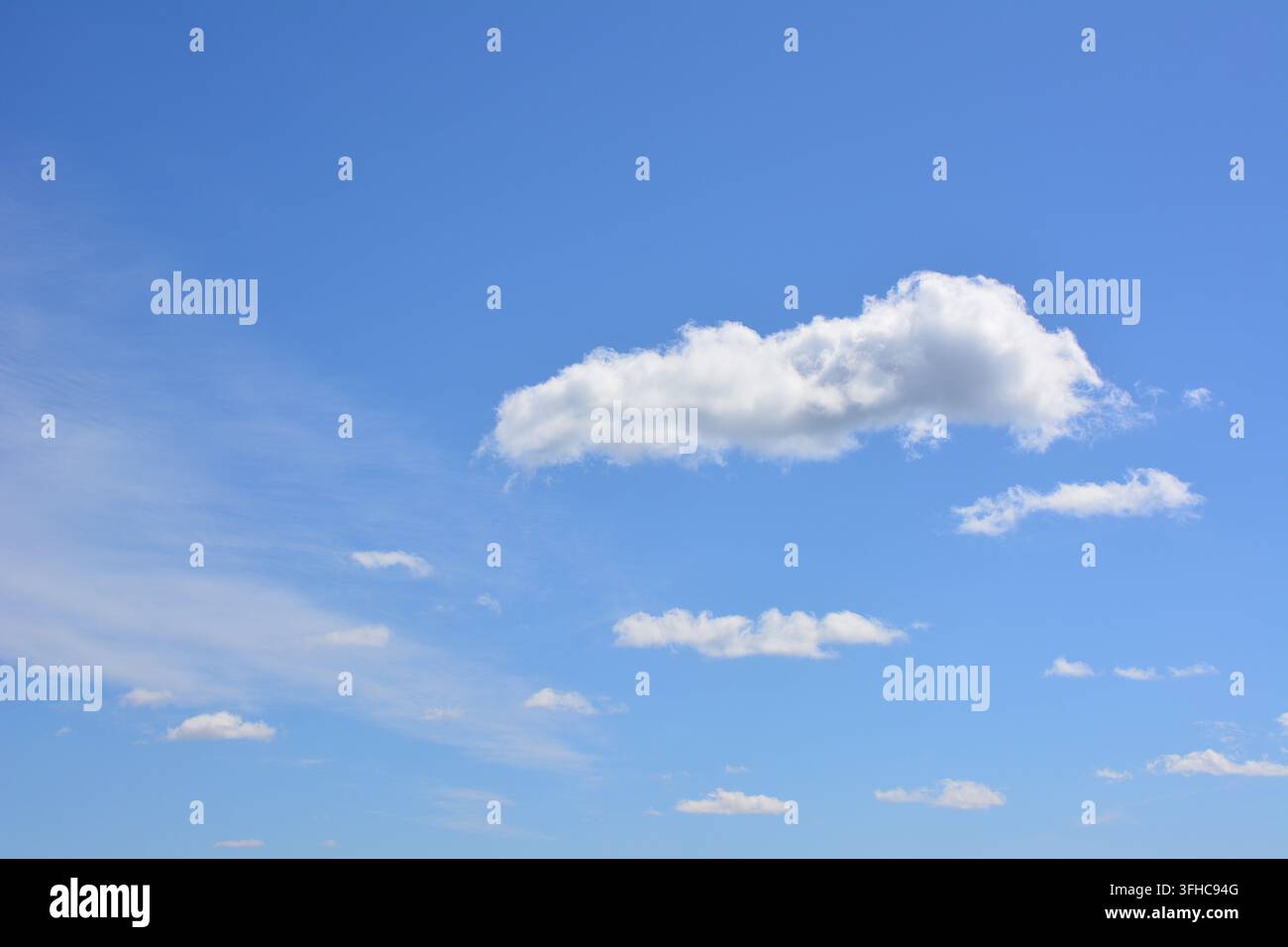 Nuages blancs épars dérivant dans un ciel bleu clair, espace de copie Banque D'Images