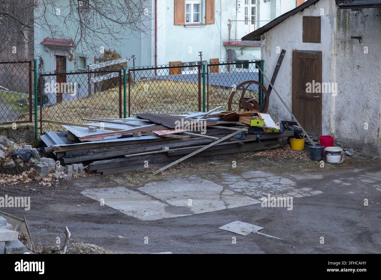 Vue d'une cour négligée présentant un petit abri abîmé et une pile étendue de planches de bois et de tôle, symbolisant le désordre et le potentiel Banque D'Images
