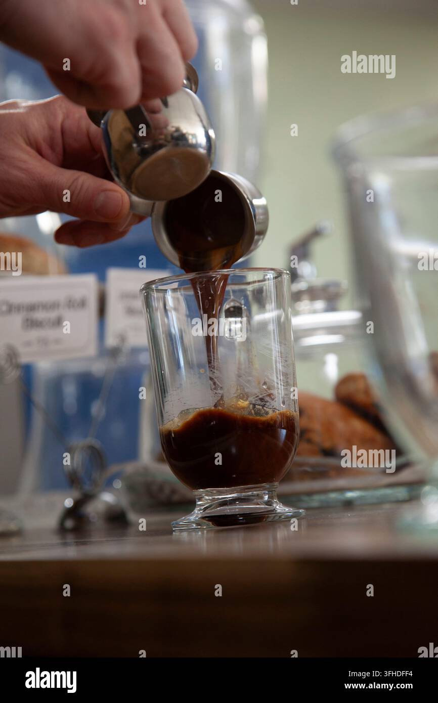 Barista versant de l'espresso dans une tasse en verre Banque D'Images