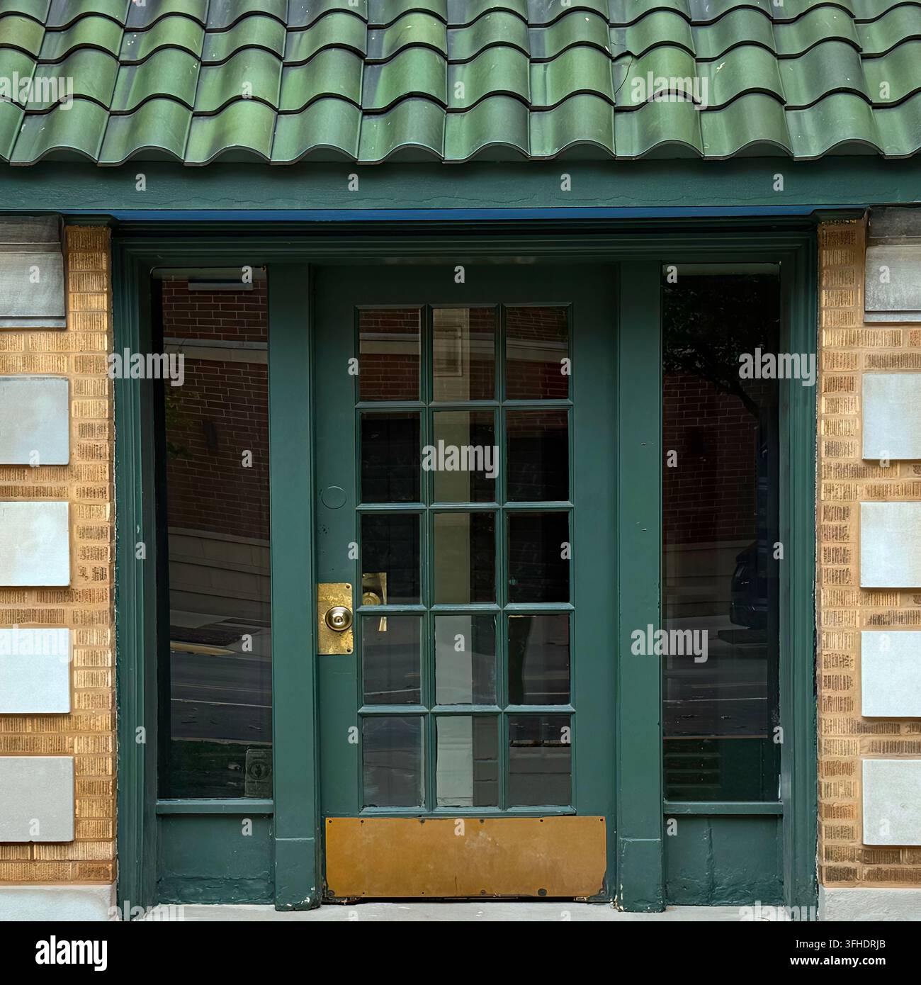 Une porte verte se trouve sous une canopée de tuiles vertes incurvées. Banque D'Images