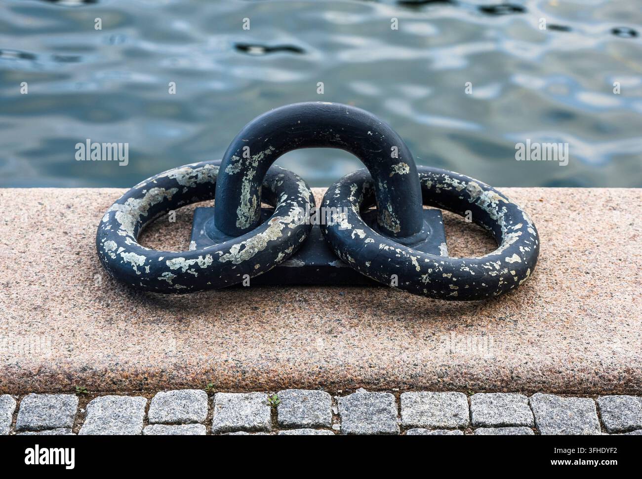 Un anneau d'amarrage en métal patiné assure une connexion sécurisée au quai du port Banque D'Images