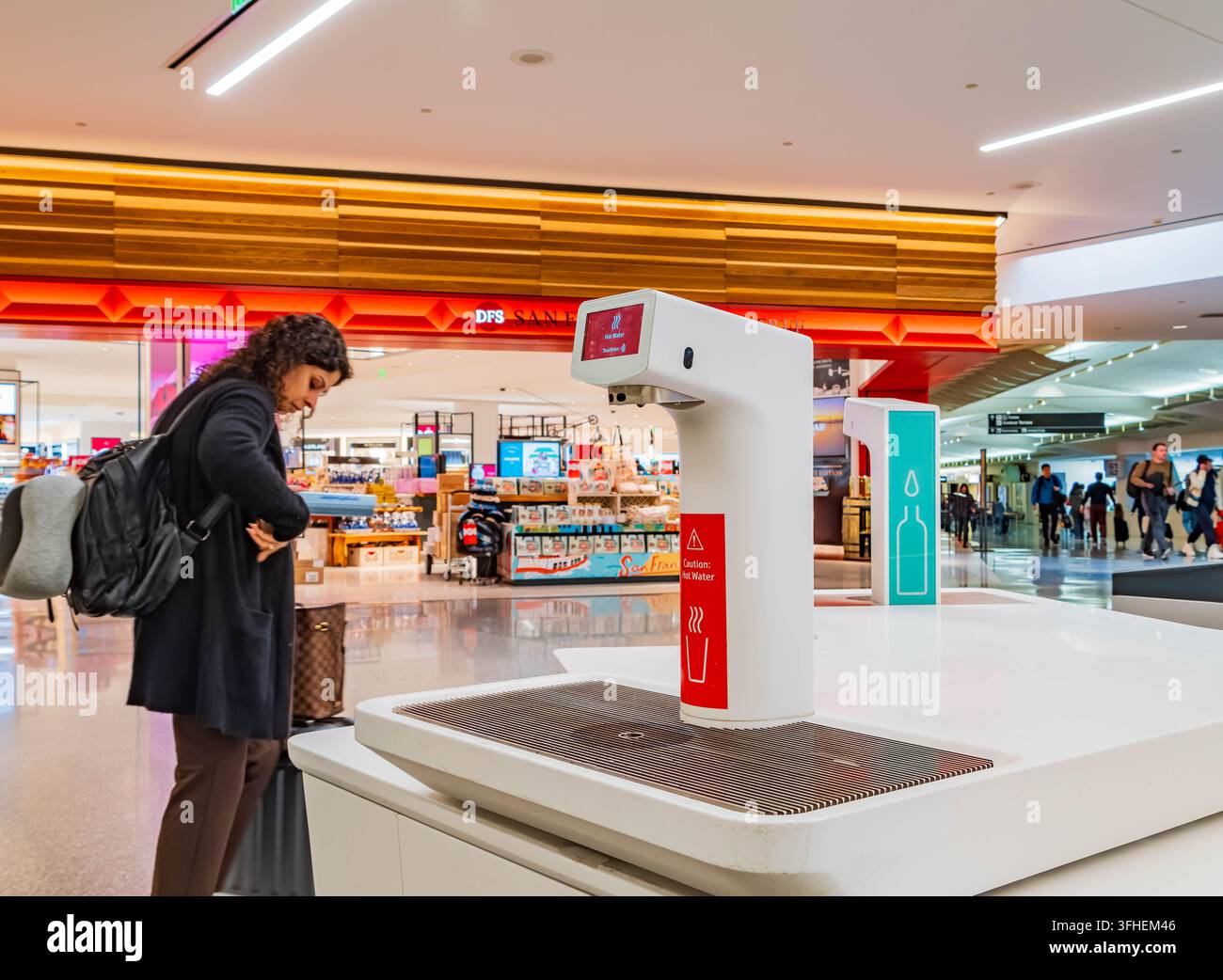 San Francisco, États-Unis, 13 AVR 2024 - Une femme avec un sac à dos se tient à une station de remplissage de bouteilles d'eau blanche dans un terminal d'aéroport brillamment éclairé Banque D'Images