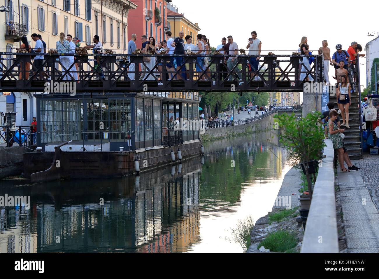 Un pont en acier bondé avec des visiteurs au-dessus du canal Naviglio Grande dans le quartier des canaux Navigli le soir.Milan,Italie Banque D'Images